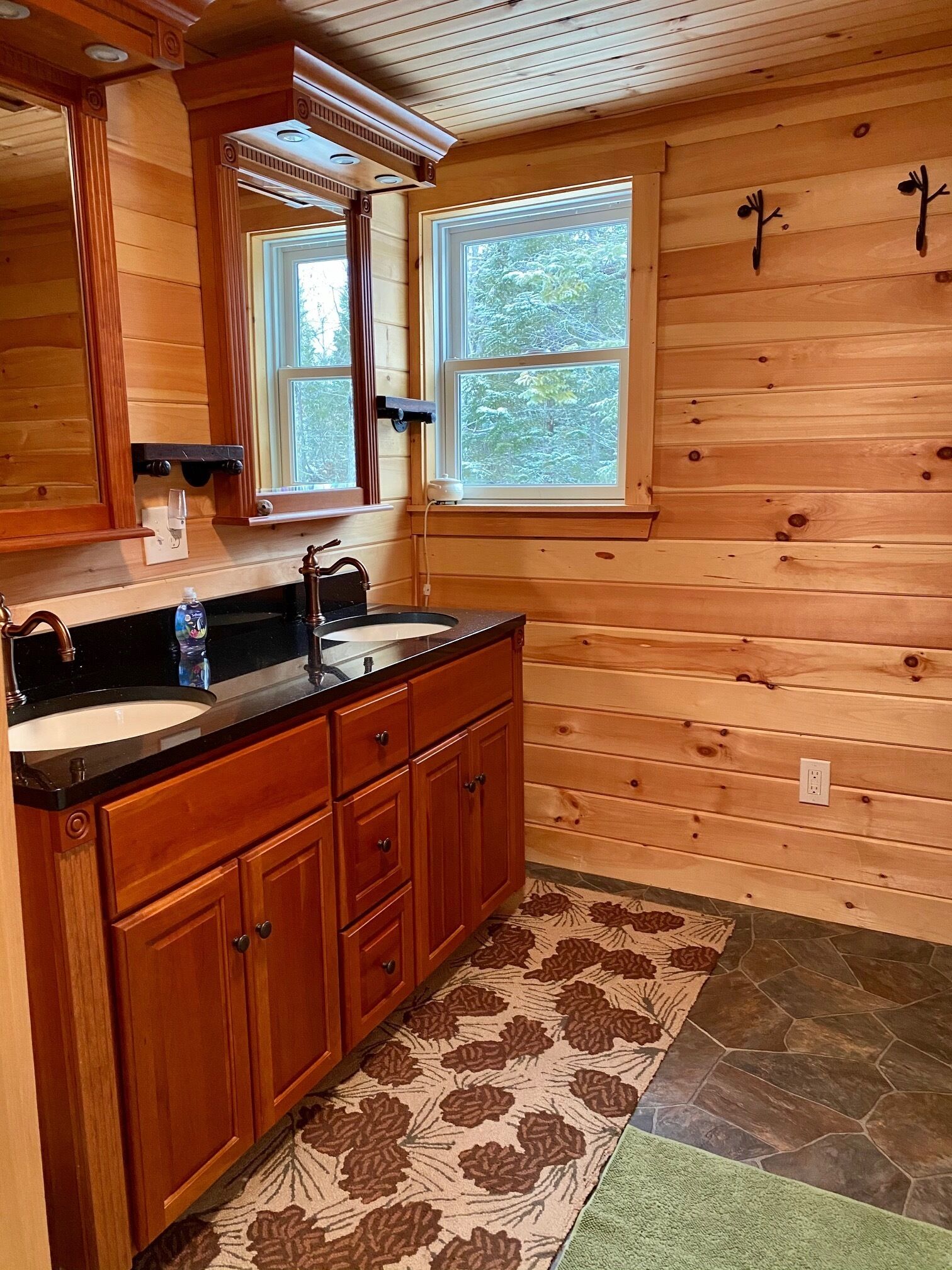 L’intérieur d’une cabane en bois, avec un plancher en bois, une grande fenêtre, un évier et des placards.