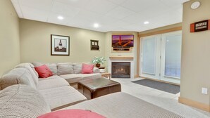 A living room with a sofa, a fireplace, and a television mounted above it.