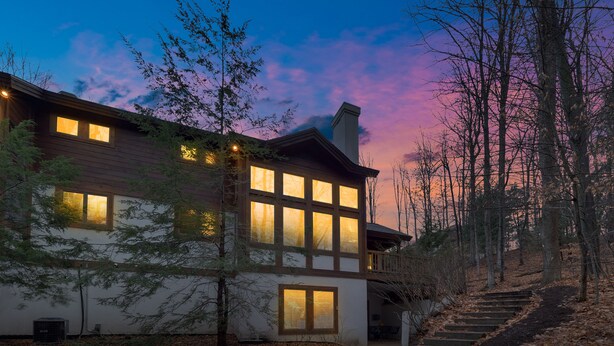 A modern two-story house with large windows and a visible staircase leading to the entrance.