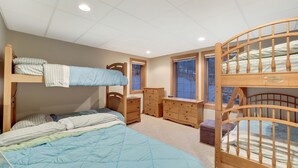 A bedroom with bunk beds, a dresser, and a window with a view.