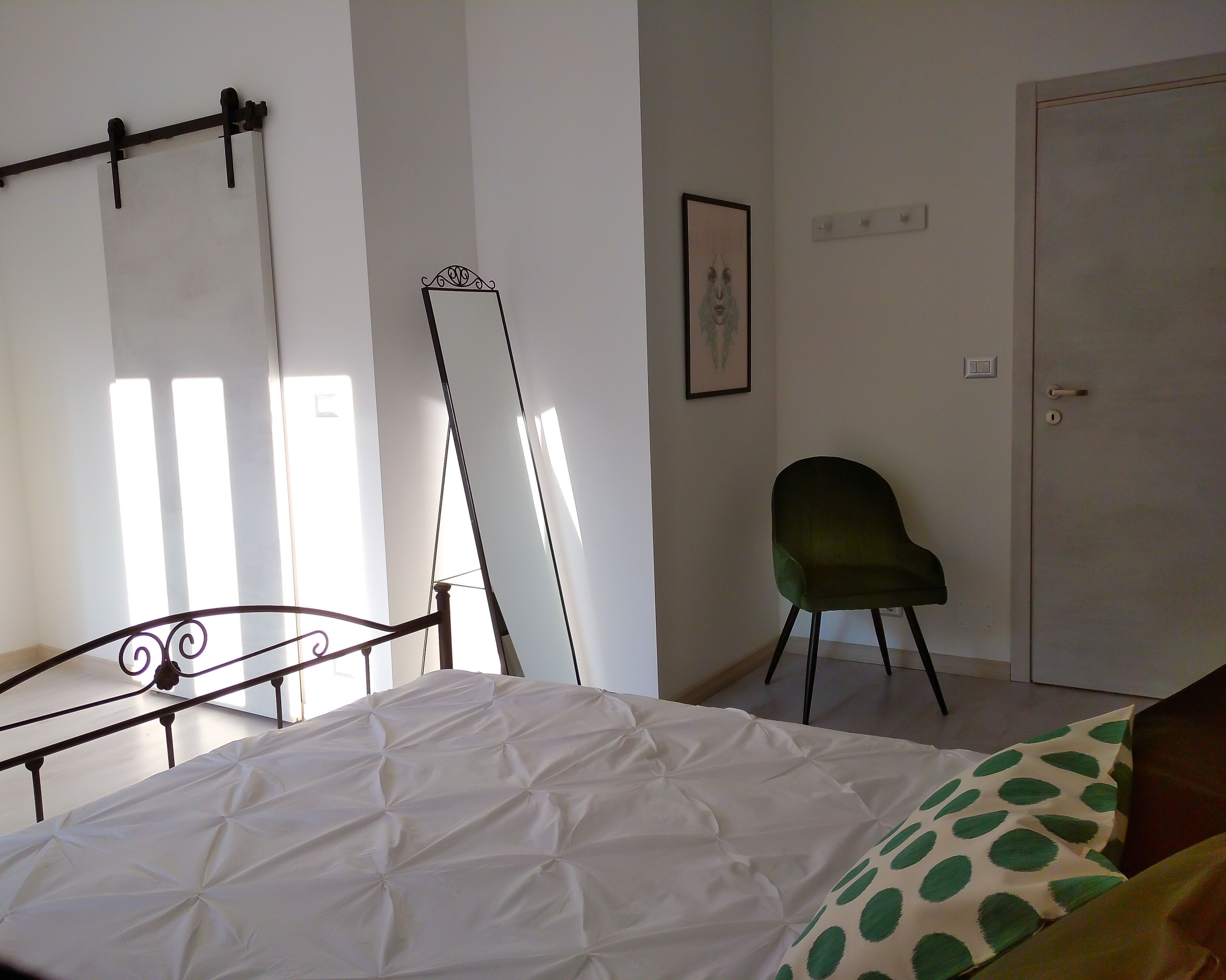 A bedroom with a bed, a chair, a door, and a window.