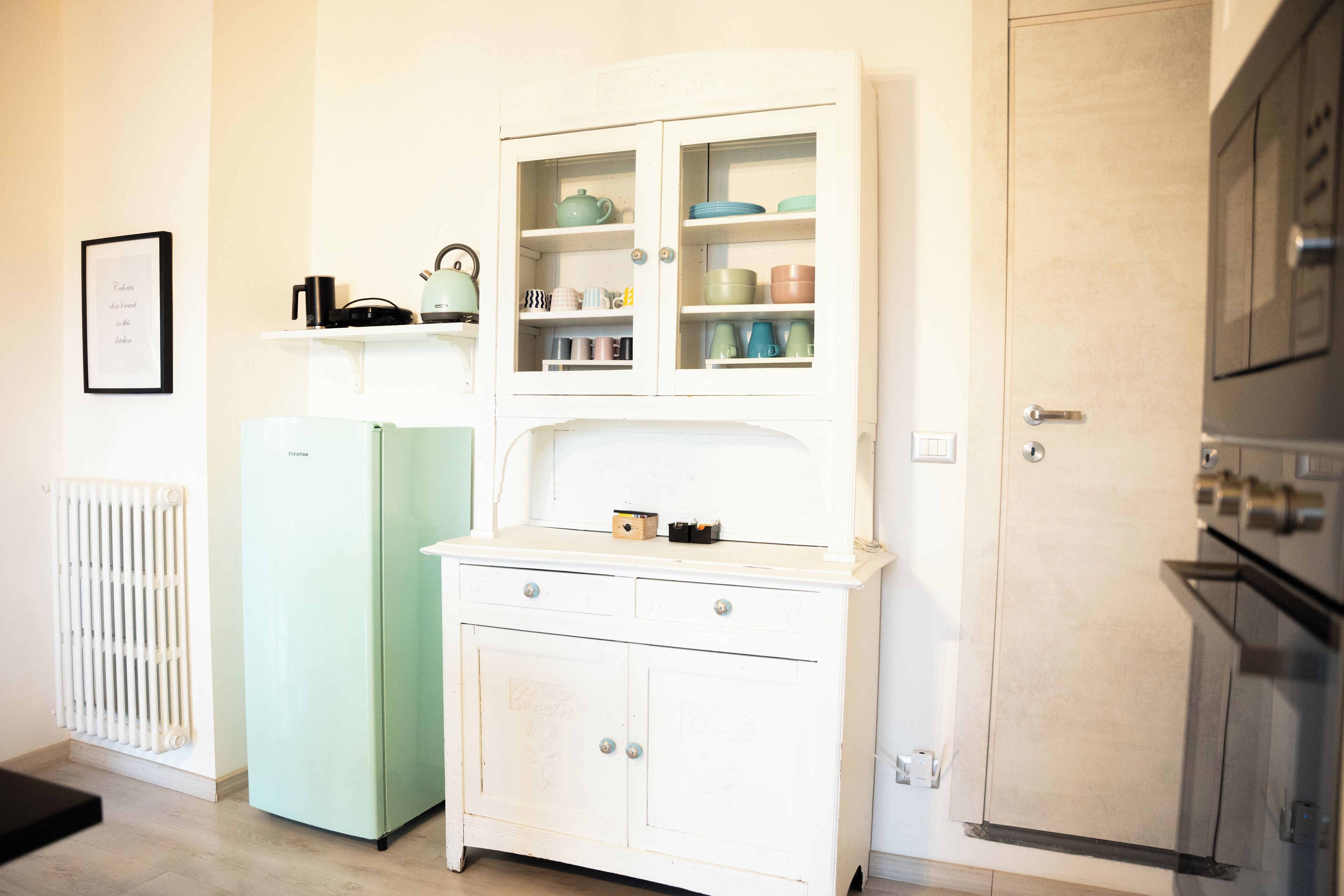 Eine Küche mit einem weißen Schrank, einem grünen Kühlschrank und einer Mikrowelle.
