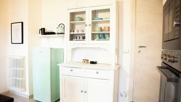Eine Küche mit einem weißen Schrank, einem grünen Kühlschrank und einer Mikrowelle.