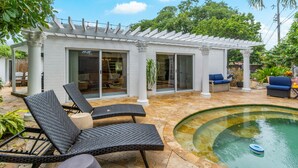 A covered patio area with a pool, lounge chairs, and a pergola.