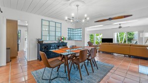 A spacious living area with a dining table, chairs, a sofa, and a ceiling fan.