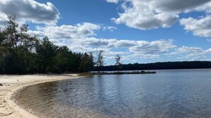 Ein Sandstrand mit klarem Wasser, eine kleine Insel und eine Felsbarriere.