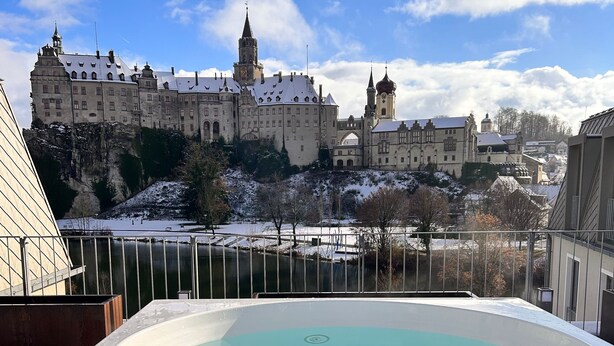 A hot tub on a wooden deck with a view of a castle-like building in the background. - Karls Hotel (Sigmaringen)