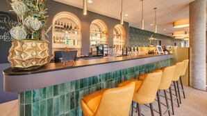 A bar area with a long counter, multiple seating options, and a decorative plant arrangement. - Karls Hotel (Sigmaringen)