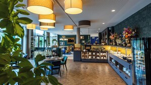 A modern interior with wooden flooring, pendant lighting, and a central island with a display of items. - Karls Hotel (Sigmaringen)