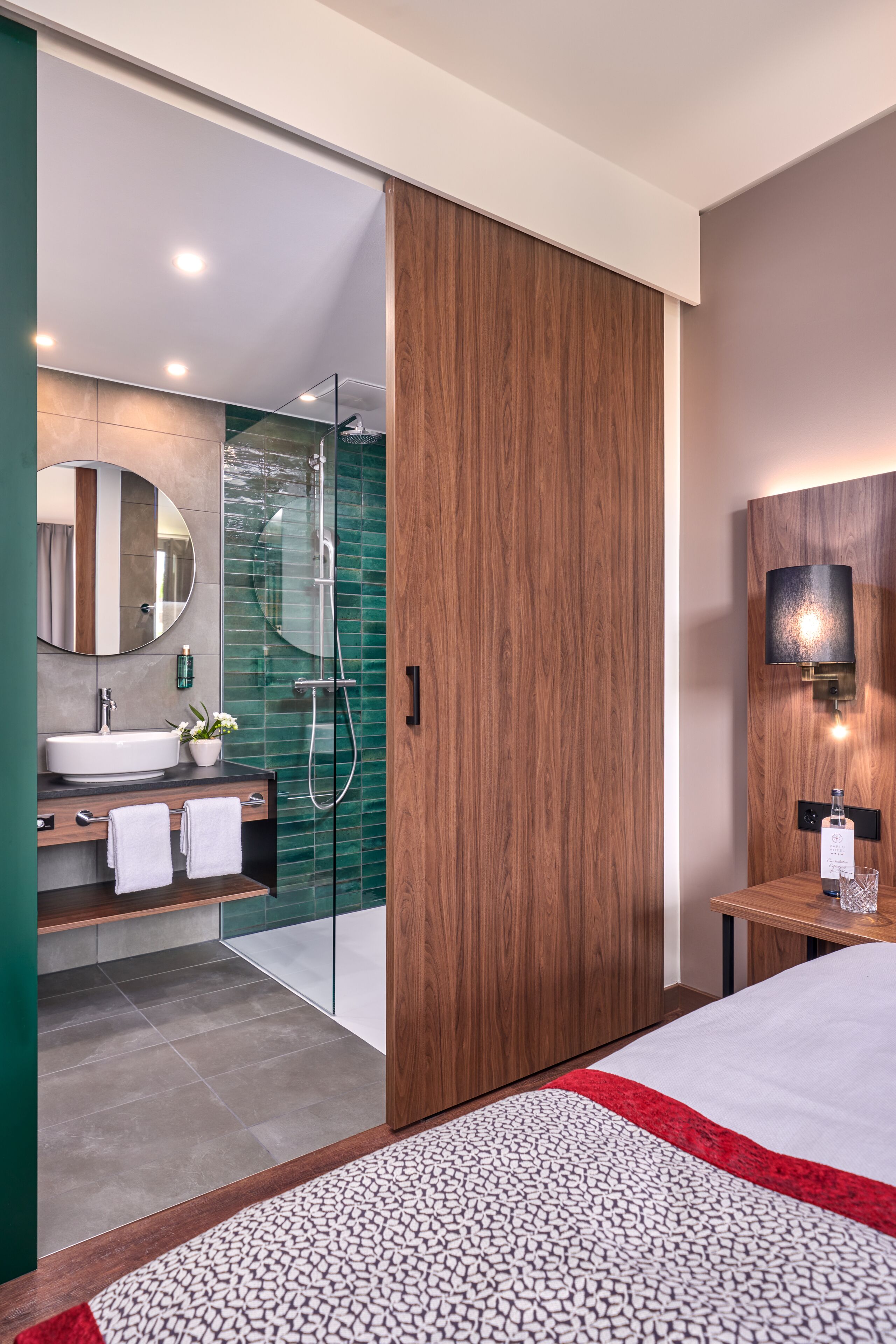 A modern bathroom with a glass-enclosed shower, a wooden vanity, and a large mirror.