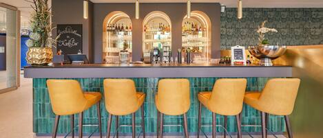 A bar area with a counter, three yellow bar stools, and a decorative plant.
