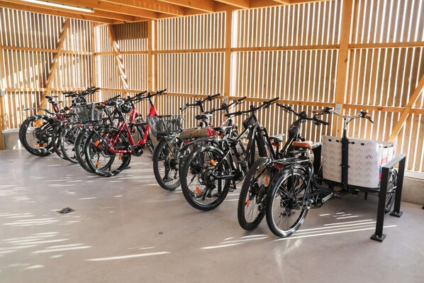 Varias bicicletas estacionadas en un espacio interior, con un panel de listones de madera al fondo.
