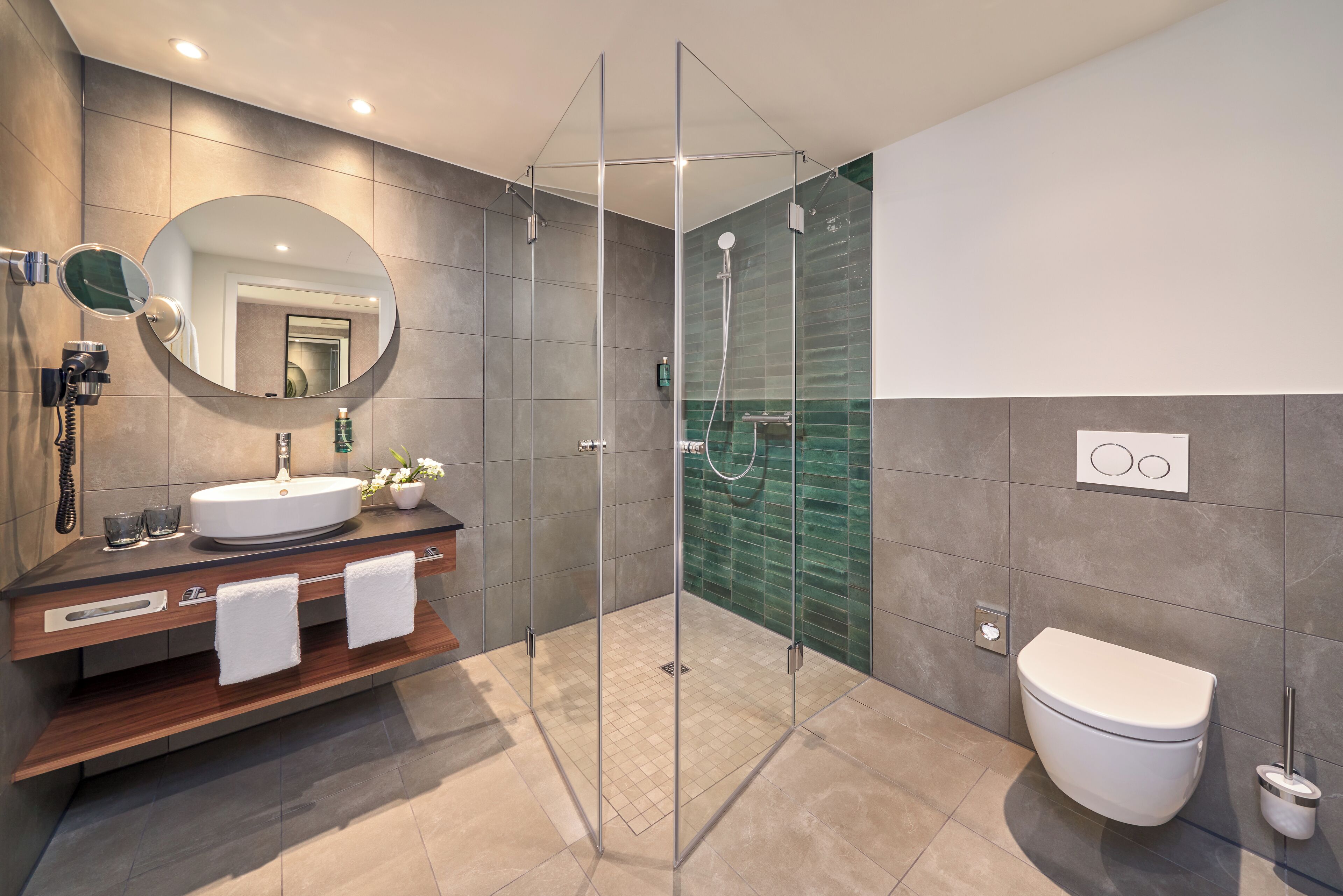 Un baño moderno con ducha de vidrio, lavamanos con espejo e inodoro.