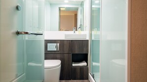 A modern bathroom with a glass shower enclosure, a white toilet, a vanity with a mirror, and a towel rack. - easyHotel Cardiff (Cardiff)