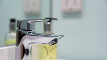 Ein modernes Badezimmer mit chromfarbenem Wasserhahn und einer durchsichtigen Glasflasche Seife.
