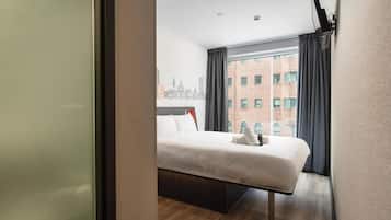 Ein Hotelzimmer mit Bett, Blick auf die Stadt und einem Vorhangfenster.