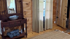 A wooden room with a wooden dresser, a mirror, a rug, and a curtain. - Country Bliss (Tishomingo)