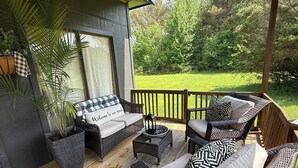 An outdoor patio with wicker furniture, a wooden deck, and a view of a green landscape. - Country Bliss (Tishomingo)