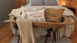 A cozy bedroom with a wooden headboard, a bed with white bedding, and pillows with text. - Country Bliss (Tishomingo)