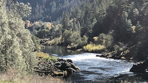 Une rivière qui traverse une vallée boisée, caractérisée par un terrain rocheux et une végétation dense.