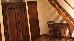 A wooden staircase with a chair and a cabinet in a room with tiled flooring. - La Grange : La Chambre Vendange (Coutouvre)