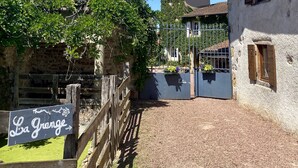 A rustic building with a stone wall, a wooden fence, and a sign reading "La Grange". - La Grange : La Chambre Vendange (Coutouvre)