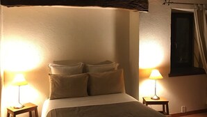 A dimly lit bedroom with a bed, two bedside lamps, and a window with curtains. - La Grange : La Chambre Vendange (Coutouvre)