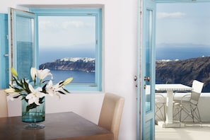 Enjoy breathtaking views of the coastline from this room's window, featuring a table with a vase of fresh flowers.