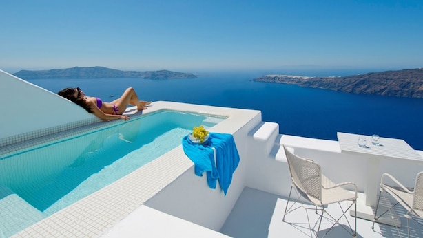 Zona junto a la piscina con vistas al mar y a las islas, una mesa con mantel azul y dos sillas.