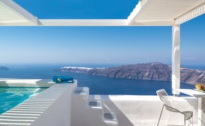 Relax by the ocean with a clear view of the distant mountains, featuring a pool and outdoor seating area.