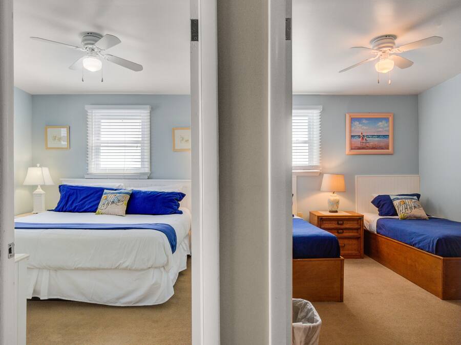 A bedroom with a bed, bedside tables, a lamp, a ceiling fan, and a window with blinds.