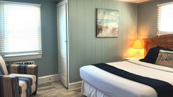A bedroom with a bed, a chair, a painting, and a lamp.
