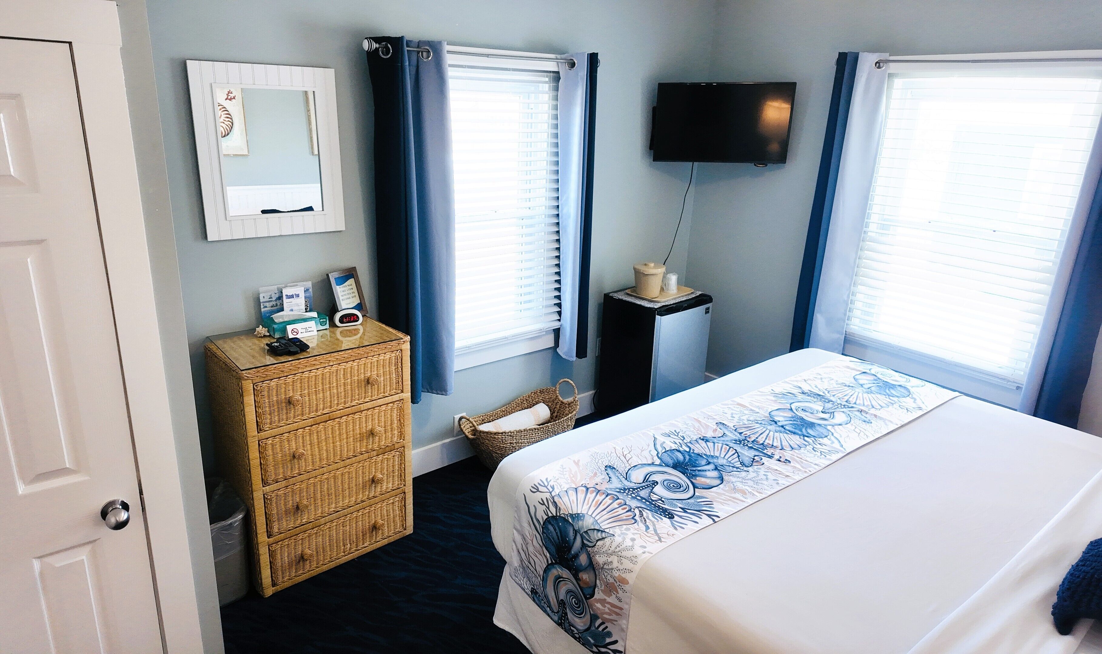 A bedroom with a bed, a dresser, a television, and a window with blinds.