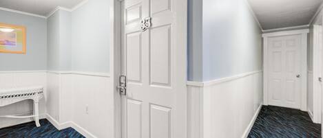A hallway with a white door marked '35', a white bench, and a patterned blue carpet.