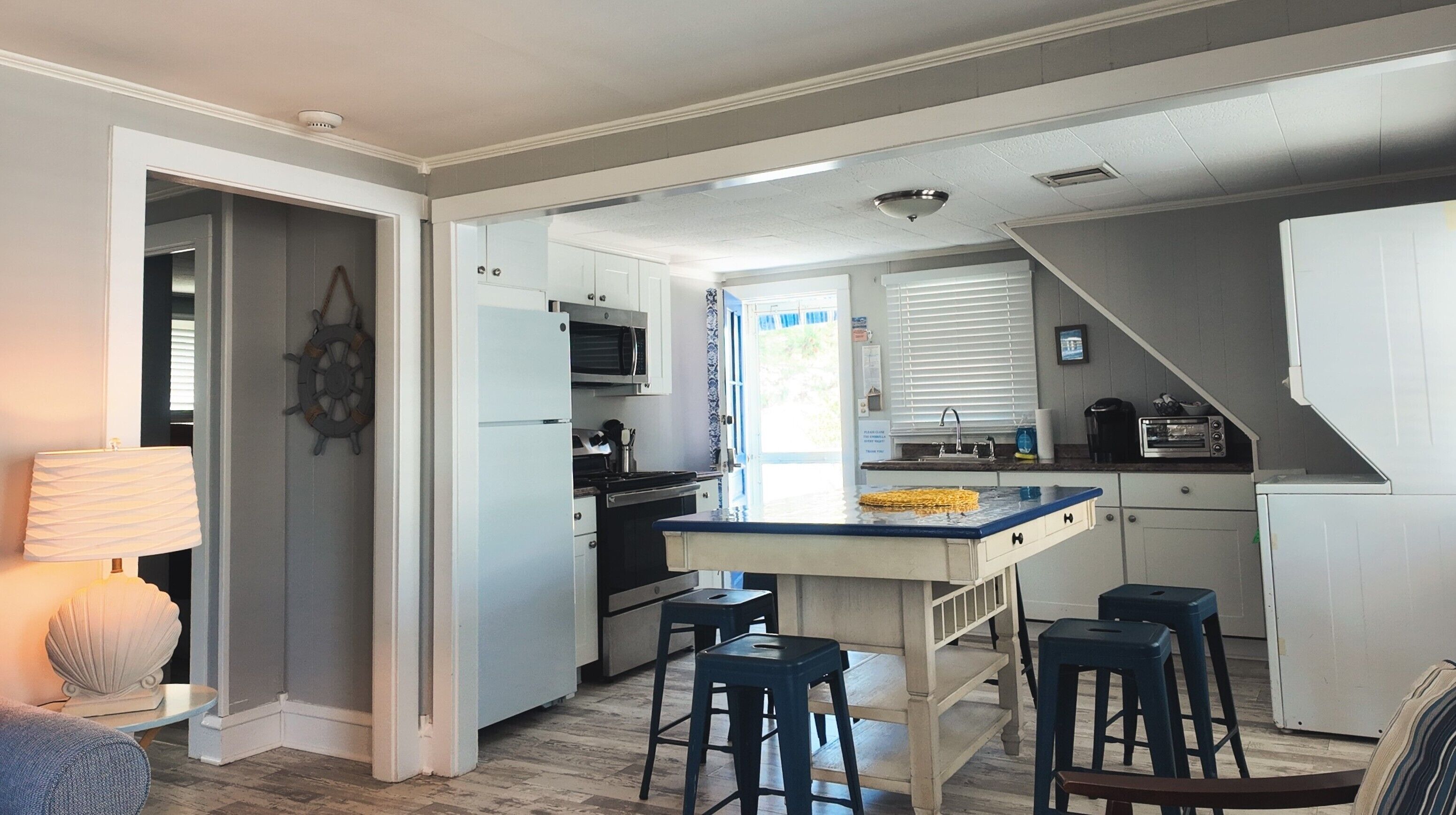 Una cocina compacta con una isla central, taburetes de bar, microondas y un lavamanos.