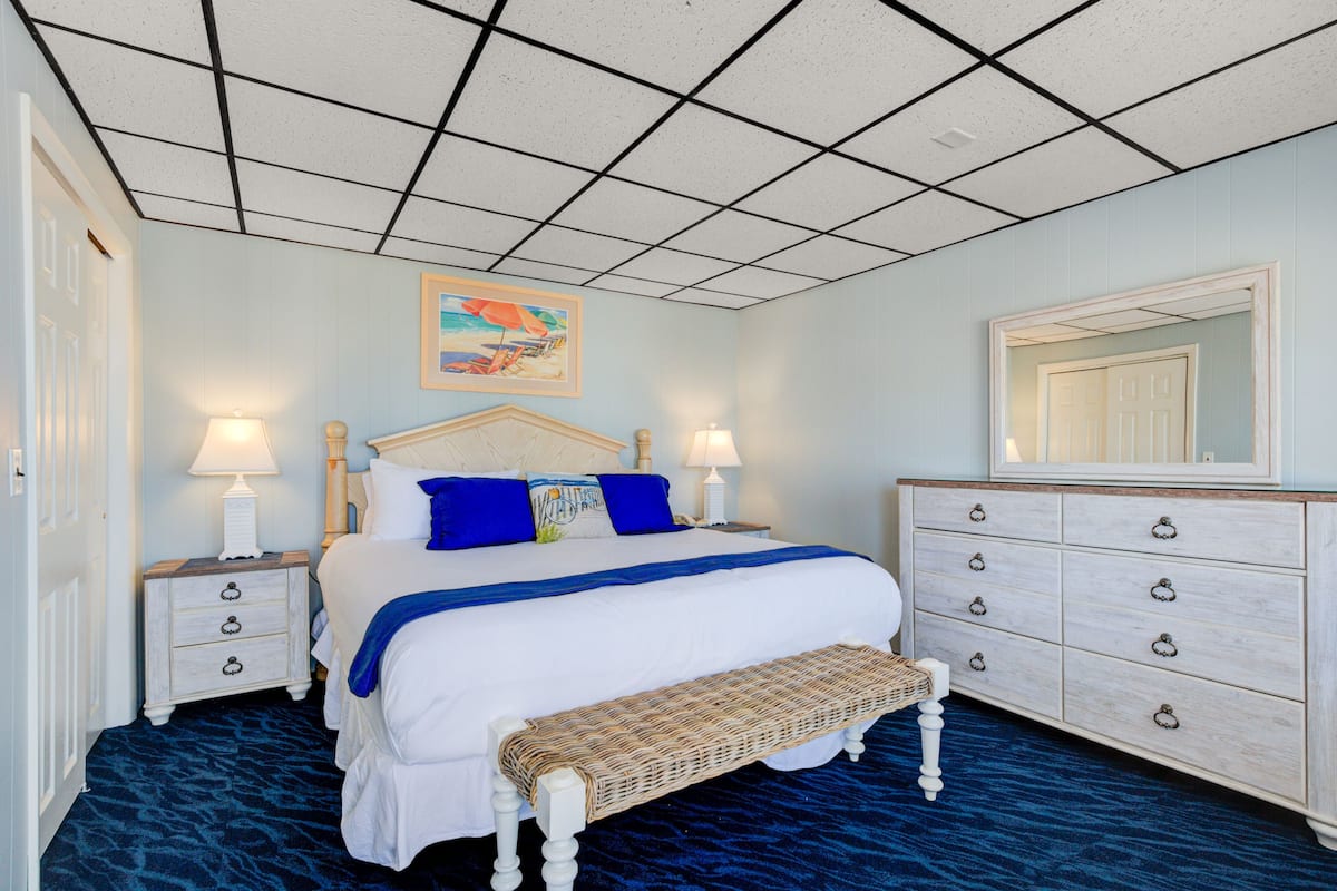 A bedroom with a bed, two nightstands, a bench, a dresser, and a mirror.