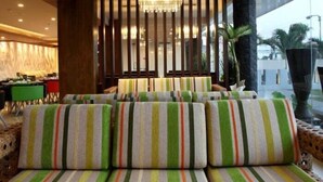 A modern lobby with striped sofas, wooden slats on the ceiling, and a view of the outdoors. - Sun Royal Hotel (Kuta)