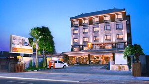A multi-story hotel with a modern facade, a well-lit entrance, and a parking area with a white van in front. - Sun Royal Hotel (Kuta)