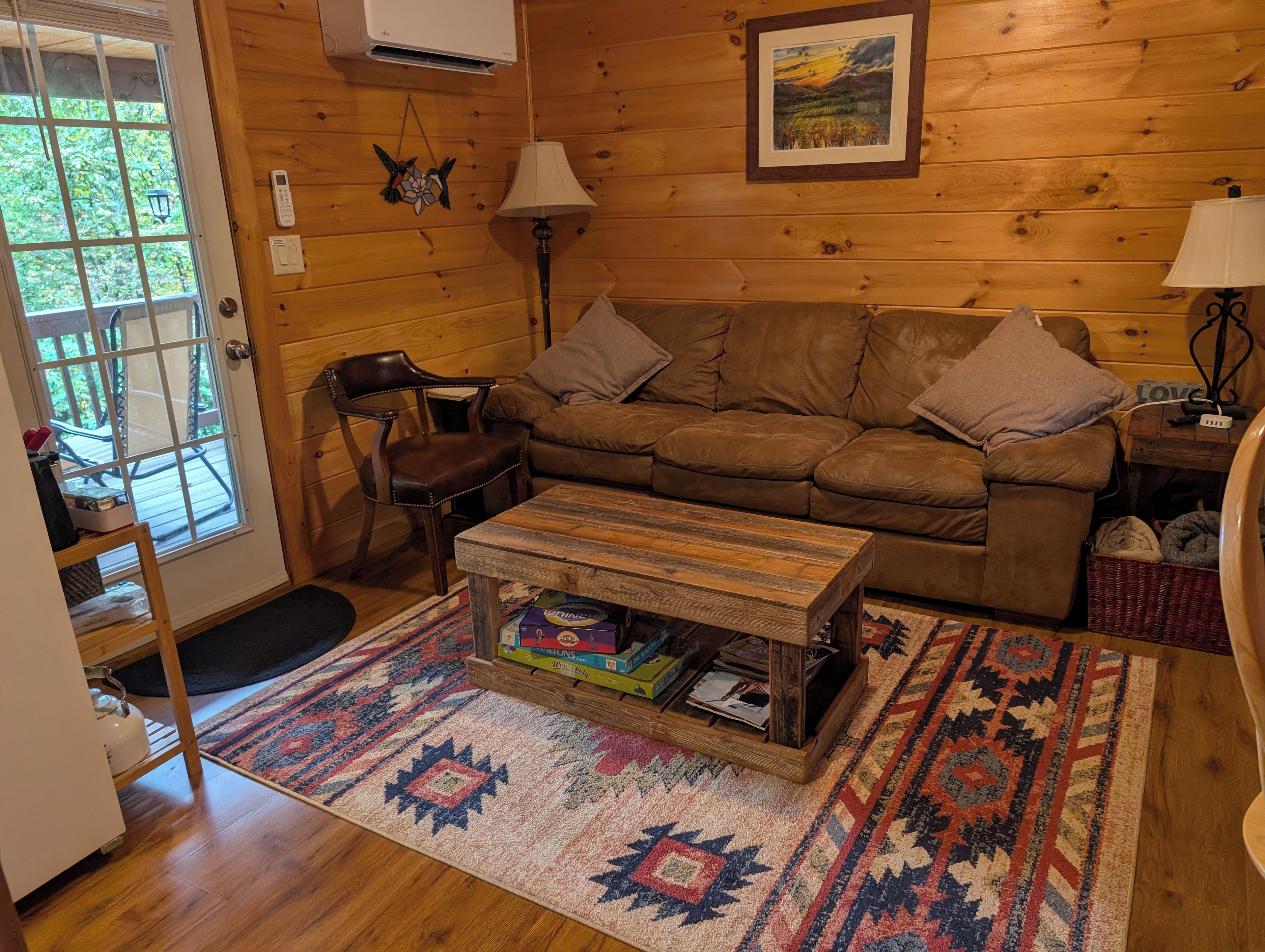 A cozy living room with a brown leather sofa, a wooden coffee table, and a patterned rug.