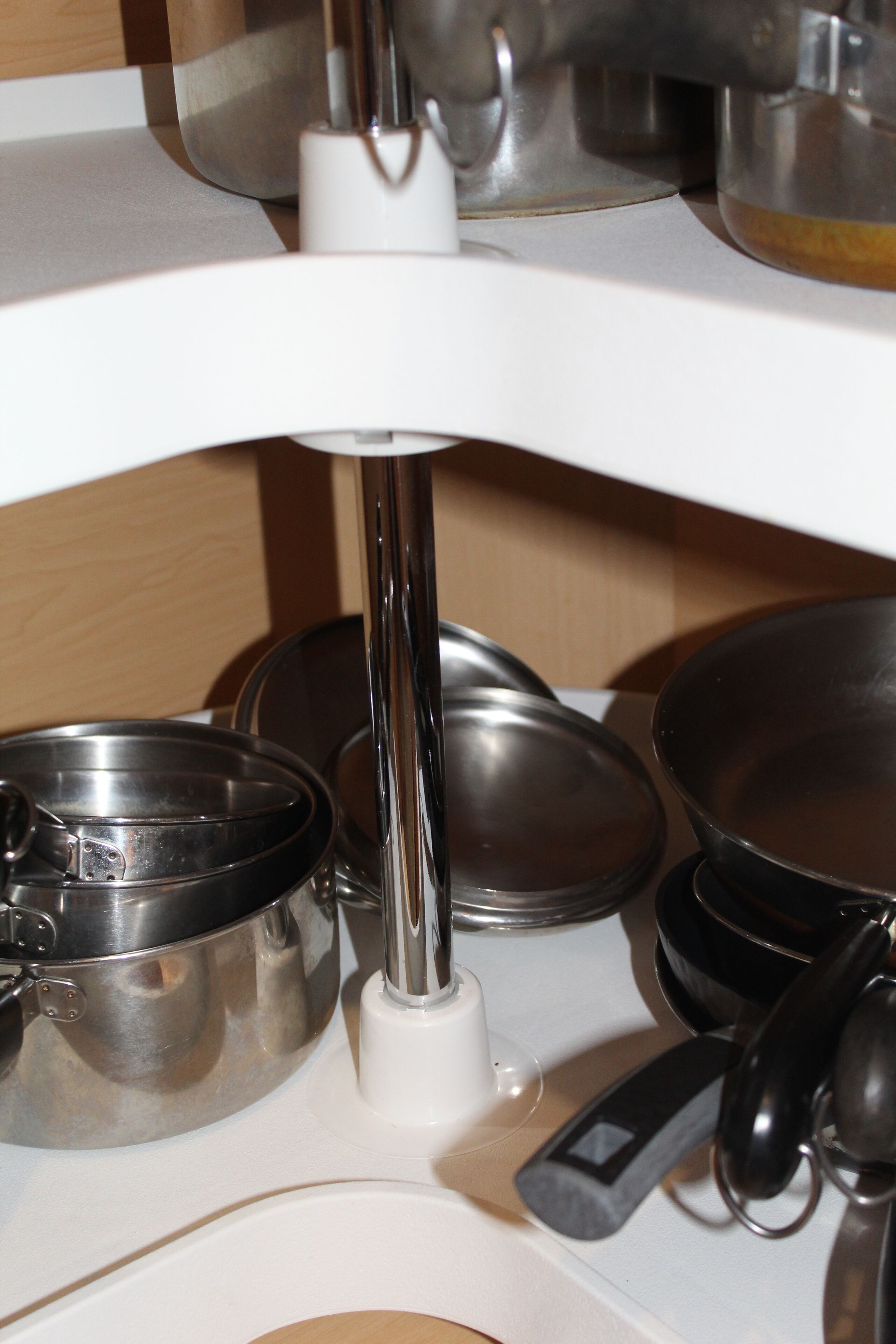 Una encimera de cocina con utensilios de cocina de acero inoxidable, incluyendo ollas y sartenes, y una tetera eléctrica blanca.