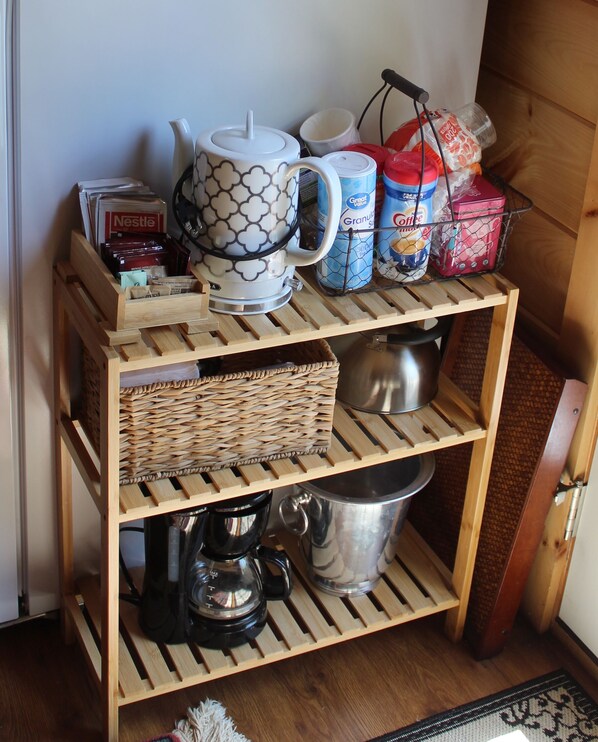 Ein Holzregal mit Aufbewahrungsboxen, einer Kaffeemaschine und Geschirr.