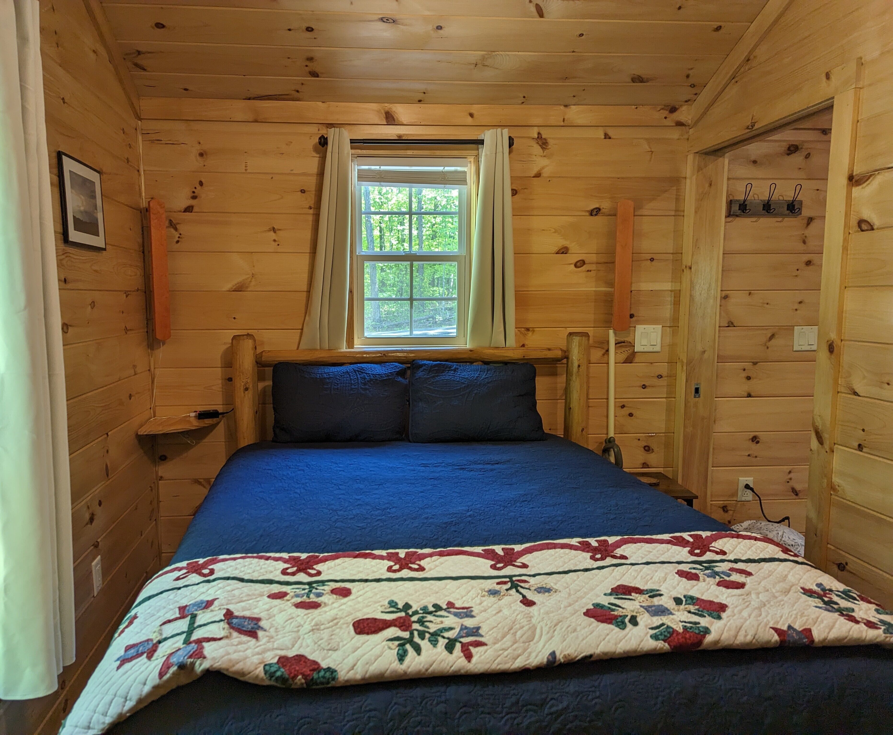 A wooden cabin room with a bed, a window, and a door.