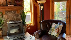 Un salon chaleureux avec une cheminée en pierre, un fauteuil en cuir et un plafond en bois rustique.