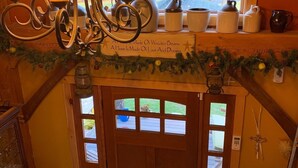 Un intérieur en bois agrémenté d’un lustre, une fenêtre donnant sur des arbres et une porte sur laquelle est fixée une enseigne.