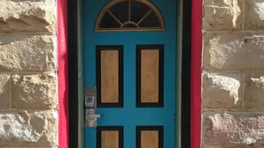 Une porte turquoise dotée d’un clavier de code, encastrée dans un mur de pierre rehaussé d’une bordure rouge.