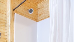 A wooden-paneled room with a white bathtub and a shower curtain. - 1bd rm, 1 bth, hotel style cabin w/ Mini fridge, micro, & tv, at Kick Back Ranch (Ramer)