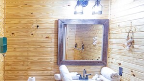 A wooden cabin bathroom with a toilet, sink, and mirror. - 1bd rm, 1 bth, hotel style cabin w/ Mini fridge, micro, & tv, at Kick Back Ranch (Ramer)