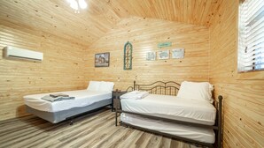 A wooden cabin room with two beds, a ceiling fan, and a 'welcome' sign. - 1bd rm, 1 bth, hotel style cabin w/ Mini fridge, micro, & tv, at Kick Back Ranch (Ramer)