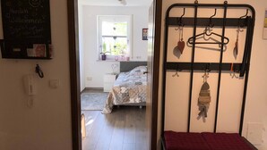 A room with a bed, a desk, a chair, and a coat rack with hangers. - Burgauer Fewo (Burgau)