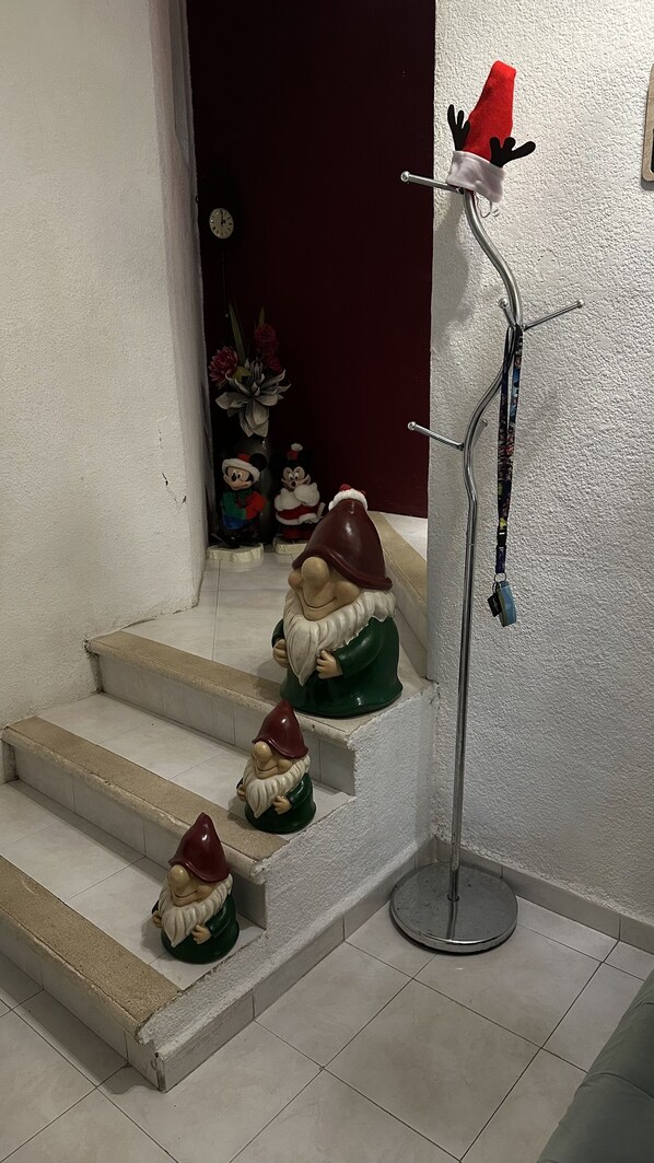 En trappa med tre trädgårdsgnomstatyetter och en klädhängare med en jultomteluva.